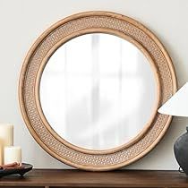 a round mirror sitting on top of a wooden table next to a lamp and vase