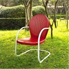 a red chair sitting on top of a green grass covered field next to a tree