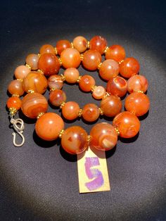 The beautiful orange color carnelian beads necklace from Himalaya Nepal This beads were used in prayer malas and used as jewelry and amulets in ancient times very smooth and shinny surface of this beads because of passage of time and usage of this beads in prayers mala and in necklace The age of this beads are more than 1000 years small size gold color brass beads are used as spacers in the necklace we provide fast and free shipping service to our customers by which can get the items by maximum Orange Amulet Necklace With Round Beads, Antique Orange Beaded Jewelry, Antique Orange Jewelry With Round Beads, Traditional Orange Carnelian Beaded Necklace, Hand-strung Orange Carnelian Beaded Necklaces, Orange Agate Beads For Jewelry Making, Orange Carnelian Beads For Spiritual Purposes, Round Carnelian Orange Beads, Orange Carnelian Beaded Necklaces With Round Beads