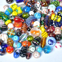 a pile of glass beads sitting on top of a white table next to each other