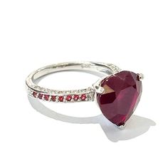 a ring with a heart shaped stone and red stones on the side, set in white gold