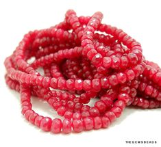 red glass beads are arranged in rows on a white surface with the beading pulled down