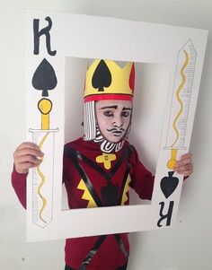 a person holding up a paper cut out of a man wearing a crown and playing card suit