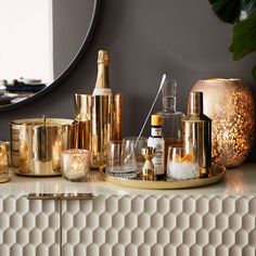 a table topped with lots of different types of bottles and glasses next to a mirror