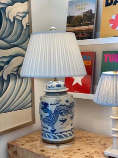 a lamp sitting on top of a wooden table next to a blue and white vase