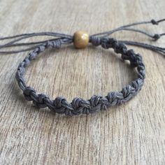 a close up of a bracelet on a wooden surface with a gold bead in the middle