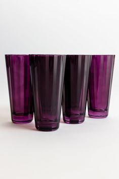 four purple glasses sitting next to each other on a white surface with no one in the photo