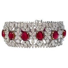 One-of-a-kind, AGL-certified, Burmese ruby and diamond wide tennis bracelet crafted in 18-karat white and 18-karat yellow gold. The 13 oval-shaped Burma rubies are AGL-certified and measure in size from 10.00 x 7.70 x 3.16 mm to 8.32 x 6.82 x 4.23mm. Each ruby slightly increases in size making the center ruby largest. The rubies are set in 18-karat yellow gold which accentuates their bold red color. The design, though intricate, is far from delicate. Diamond clusters encircle the rubies with an Luxury Ruby Bracelet Elegant Style, Luxury Ruby Bracelet For Anniversary, Burmese Ruby, Diamond Pendants Designs, Bracelet Tennis, Ruby Bracelet, Diamond Pendants, Wide Bracelet, Expensive Jewelry