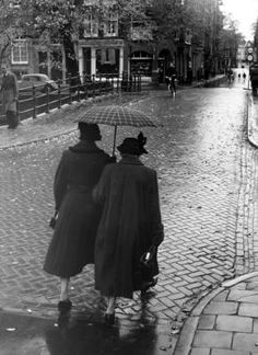 two people are walking down the street with an umbrella