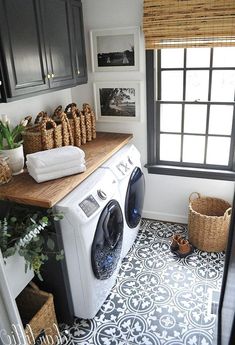 a washer and dryer in a small laundry room with black cabinets, white walls and flooring