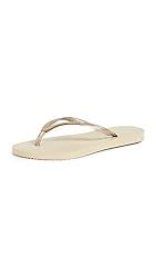 a pair of women's flip flops in white with gold straps and toe