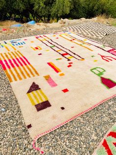 colorful rugs on the ground with rocks and trees in the backgrouund