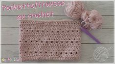 a pink crochet bag with yarn and ball of yarn next to it on a wooden surface