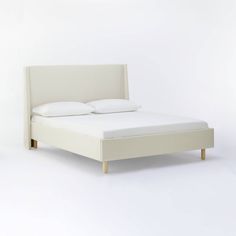 a bed with white sheets and pillows on it