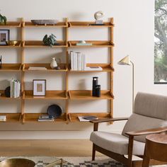 a living room with a chair, bookshelf and pictures on the wall behind it