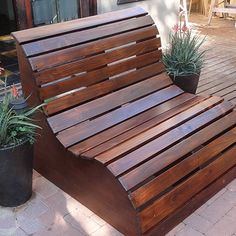 a wooden bench sitting next to a potted plant on top of a brick patio