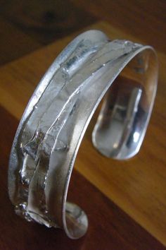 "Silver bracelet or bangle, wrist size 60 mm (2 3/8\"). Solid silver band in an anticlastic surface. The band it self has a frosted look. The decoration of the multiple silver composition is highly polished. The width of the bracelet is 19 mm (3/4\"). The total weight is about 50 grams. Your price for this bracelet includes the costs of shipping, with track & trace." Unique Silver Hand Cast Bangle, Unique Hand Cast Silver Bangle, Silver Fusion Cuff Bracelet With Oyster Design, Artistic Silver Cuff Bangle Bracelet, Artistic Silver Cuff Bracelet Bangle, Artistic Silver Bangle Cuff Bracelet, Silver Wide Band Metal Bangle, Modern Silver Band Bracelet, Artistic Silver Bangle Bracelets