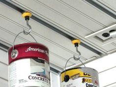 two tin cans hanging from the ceiling with paint on them and one can being used as a light fixture