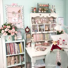 a white desk topped with lots of shelves filled with books and other items next to a window