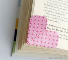 an open book with a pink origami heart on it's cover and a poem in the background