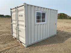 a white shipping container sitting on top of a dirt field