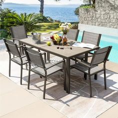 an outdoor dining table with chairs next to a swimming pool