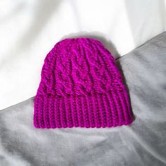 a pink knitted hat laying on top of a bed