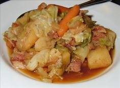 a white plate topped with meat and veggies covered in gravy next to chopsticks