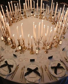 the table is set with many candles and place settings for dinner guests to sit at