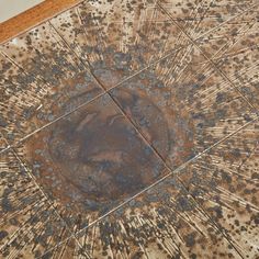 an old tile floor that has been stained brown and blue with some spots on it