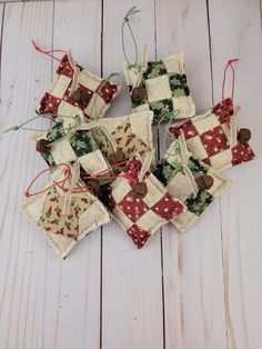 several pieces of fabric hanging from strings on a white wooden surface with red and green decorations