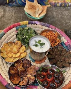 an assortment of food is displayed on a wicker platter with dip and chips