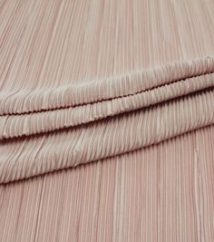 a close up view of a pink bed sheet with pleated edges and two pillows