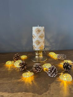 some pine cones are sitting on a table next to a lit candle and other decorations