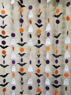 halloween decorations with bats and ghostes hanging from the ceiling in front of a wall