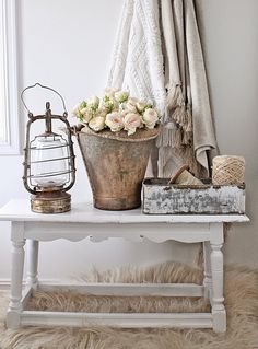 a white table topped with a metal bucket filled with flowers