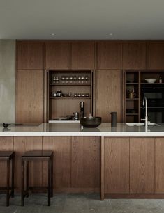 a large kitchen with wooden cabinets and white counter tops, along with two bar stools