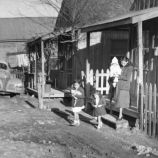 an old black and white photo of people standing in front of a house with a fire hydrant