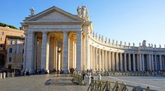 an old building with columns and statues on the front, surrounded by people walking around