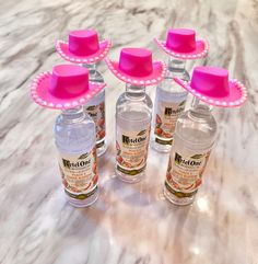 six bottles with pink hats on top of them