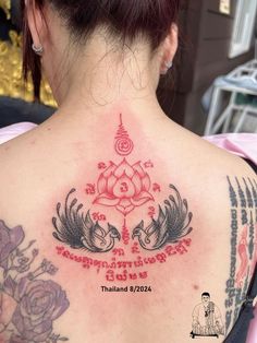 the back of a woman's neck with tattoos on it and an inscription in thai writing