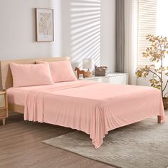 a bed with pink sheets and pillows in a room