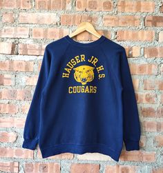 Vintage 80s Hauser JR. H.S. Cougars by Champion Sweatshirt Cougars Crewneck Cougars Pullover Embossed Logo Blue Color Women's Fit S Label : Champion Label Size : L (refer the measurement) Made in USA Materials from 92% Cotton 8% Polyester Used Item With Condition 7/10 Refer Picture. No Stain and No Holes. Lay Down Flat Measurement : - Width (armpit to armpit) and: 21 Inches - Length (shoulder to end of garment): 25 Inches We are selling used clothing with good condition. DO NOT EXPECT the item i Vintage Crew Neck Tops For School, Vintage Blue T-shirt For Fall, Vintage Pre-shrunk Crew Neck Sweatshirt, Vintage Pre-shrunk Winter Sweatshirt, Vintage Blue Sweatshirt For College, Retro Blue Sweatshirt With Screen Print, Vintage Crew Sweater For College, Retro Blue College Sweatshirt, Vintage Crew Neck Sweater For College