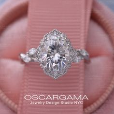 an engagement ring with three stones on it in a pink velvet case and the words oscaragma jewelry design studio nyc