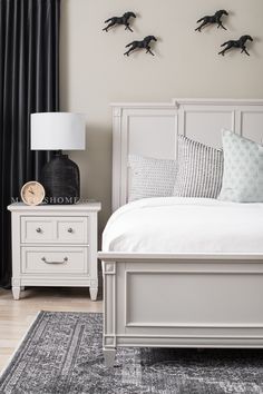 a white bed sitting in a bedroom on top of a wooden floor next to a lamp