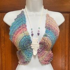 a white mannequin wearing a multicolored crocheted scarf and necklace