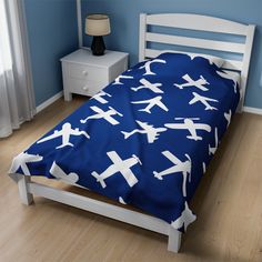 a bed with an airplane print on it in a blue room next to a night stand