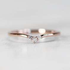 a rose gold ring with two diamonds on it, sitting on top of a white surface