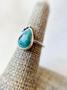 A Pear or Teardrop shaped Hubei Turquoise cabachon with feather-like matrix is accented with 3 Fine Silver Dots and delicately bezel set onto a simple Sterling Silver Band.  Gorgeous! Each piece of GreenHillJewelry is handmade in our El Dorado Hills, CA studio. Please allow for natural variations that may occur.  This order will ship in 1-2 business days via first class USPS unless Priority Shipping is added at checkout. Teardrop Bezel Set Jewelry, Elegant Turquoise Teardrop Rings, Bohemian Teardrop Turquoise Adjustable Ring, Bohemian Adjustable Teardrop Turquoise Ring, Bohemian Teardrop Turquoise Ring, Turquoise Teardrop Gemstone Rings, Bohemian Sterling Silver Turquoise Teardrop Ring, Bohemian Cabochon Teardrop Jewelry, Unique Adjustable Teardrop Turquoise Ring