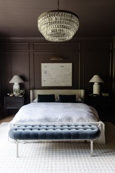 a bedroom with a large bed and chandelier hanging from it's ceiling